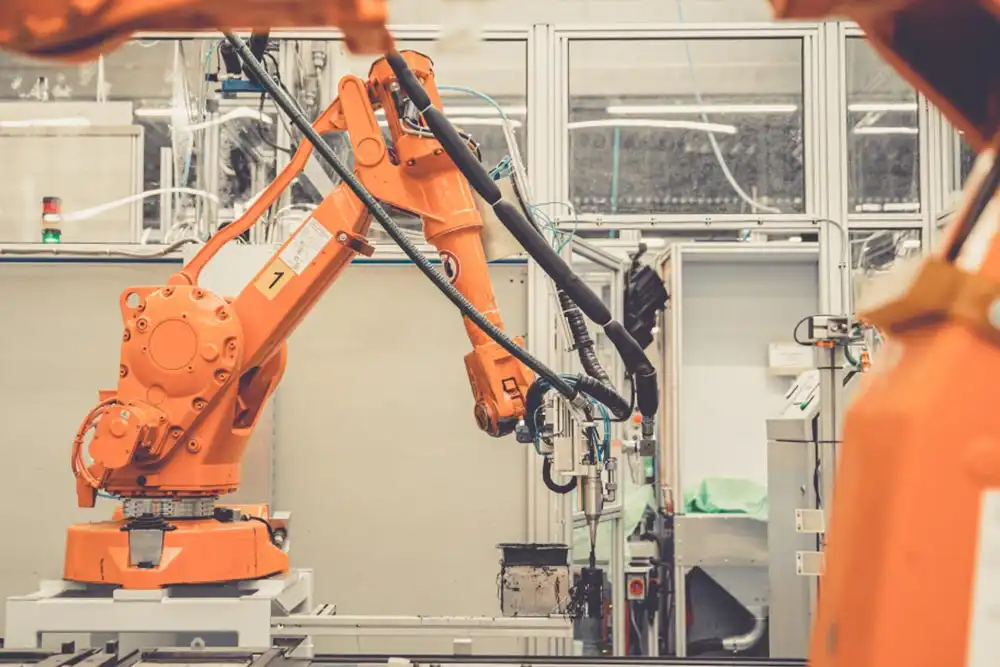 Guarded industrial robot cell with safety fencing and operator panel showing ISO 10218-2:2025 safety